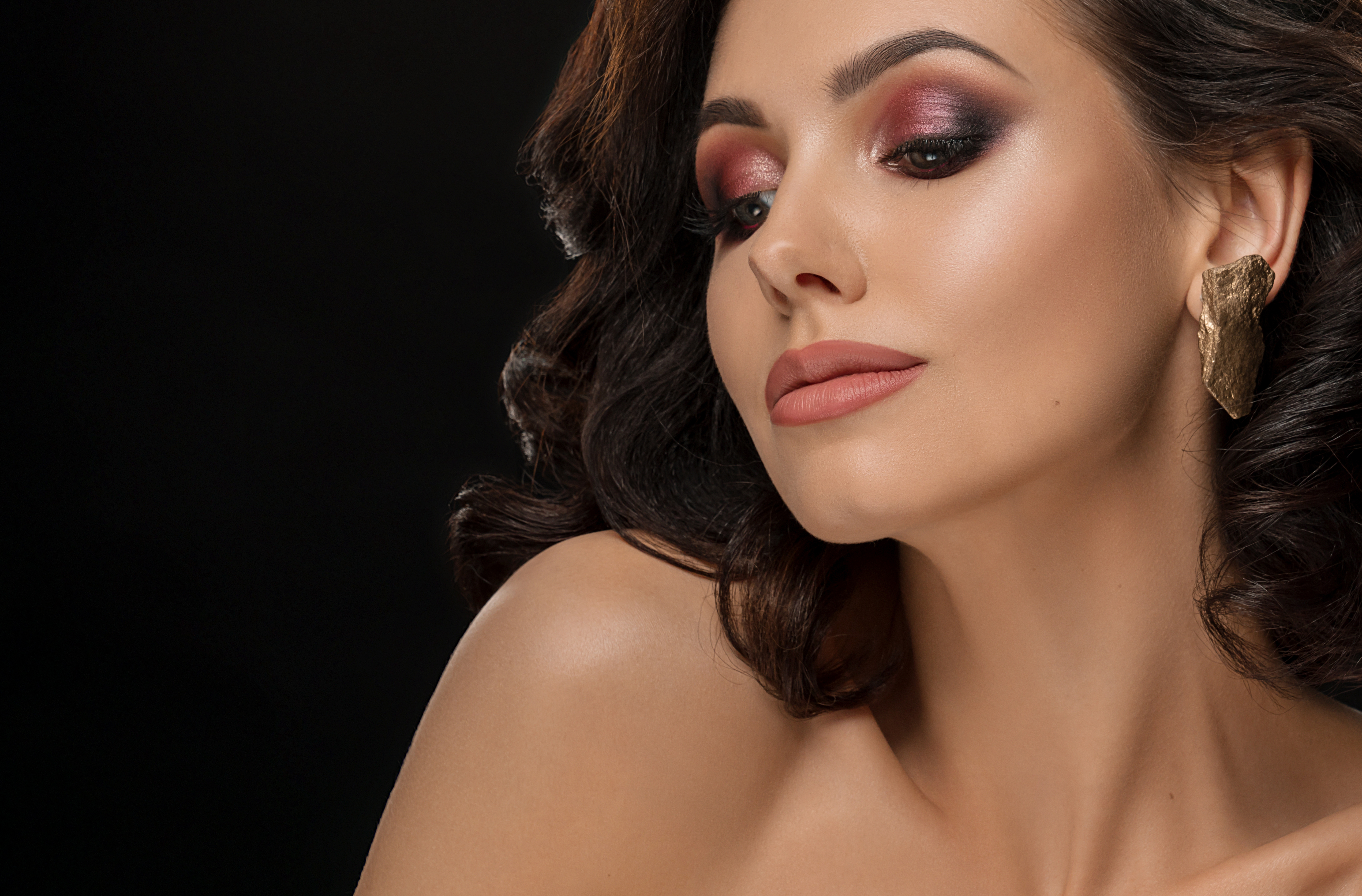 Elegancka para w świątecznym wnętrzu; kobieta w czerwonej sukience prezentuje makijaż wieczorowy wykonany w studio Syrenka Toruń.