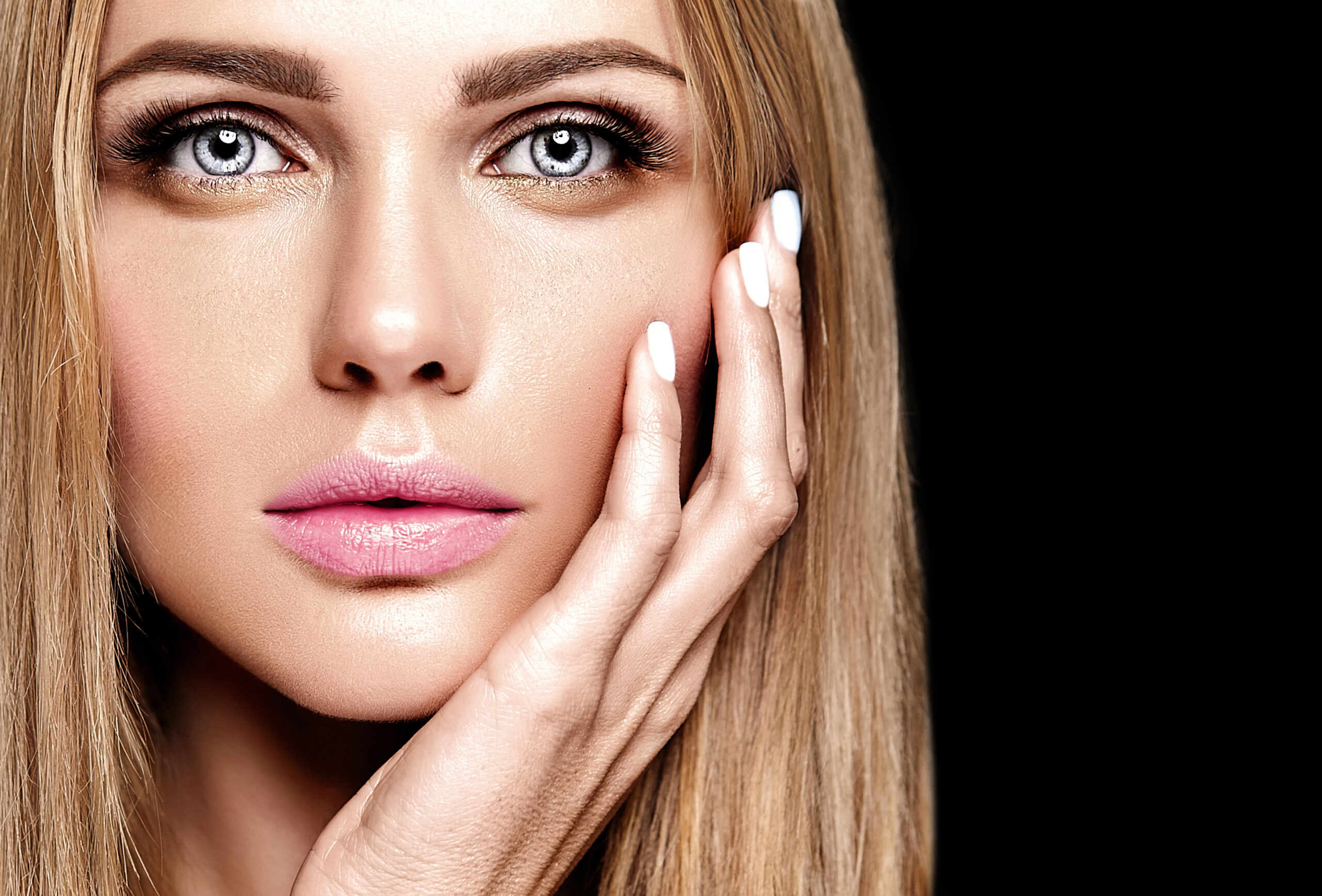 Kobieta w czerwonej sukience prezentuje makijaż oczu w stylu glamour w nastrojowym, świątecznym wnętrzu.