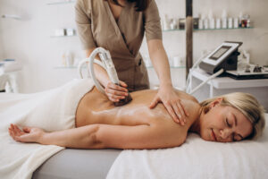 Kobieta poddawana zabiegowi endermologii przy użyciu nowoczesnego urządzenia do masażu podciśnieniowego.